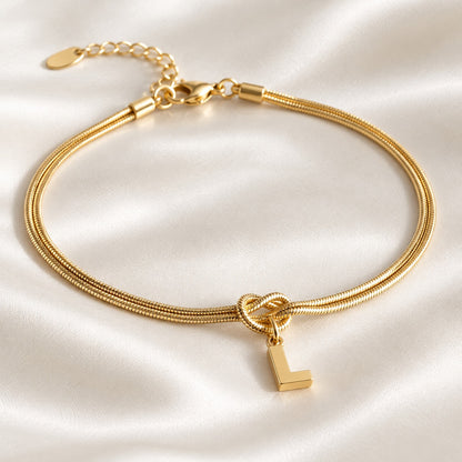 Bracelet nœud or avec initiale L sur satin ivoire