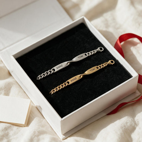 Coffret Liora ouvert sur un drap : bracelet argent et bracelet or gravés ANNE · TOM